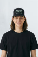 Person wearing a black cap with 'velvet' logo on a background