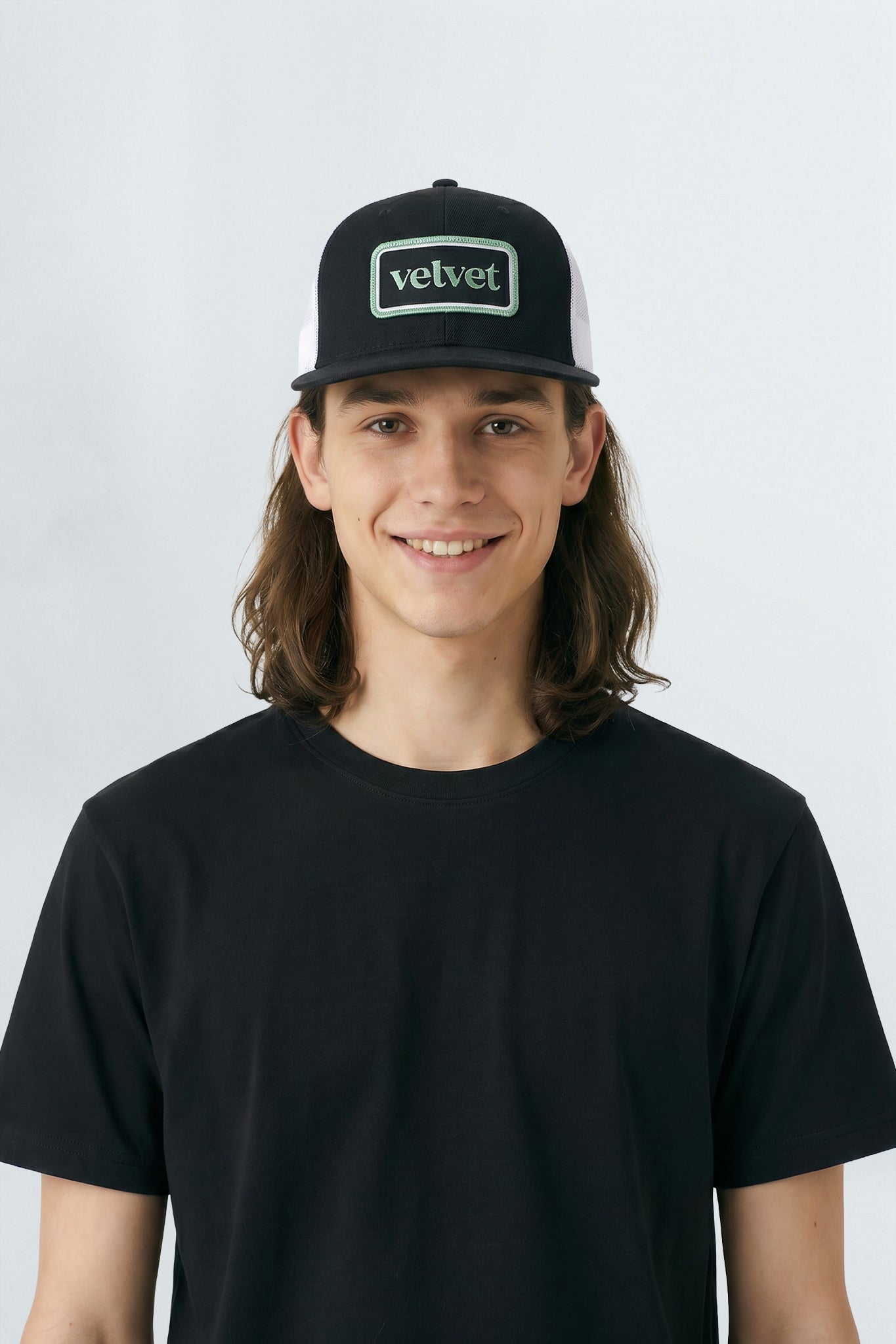 Person wearing a black cap with 'velvet' logo on a background