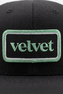 Black cap with a green 'velvet' patch on a white background