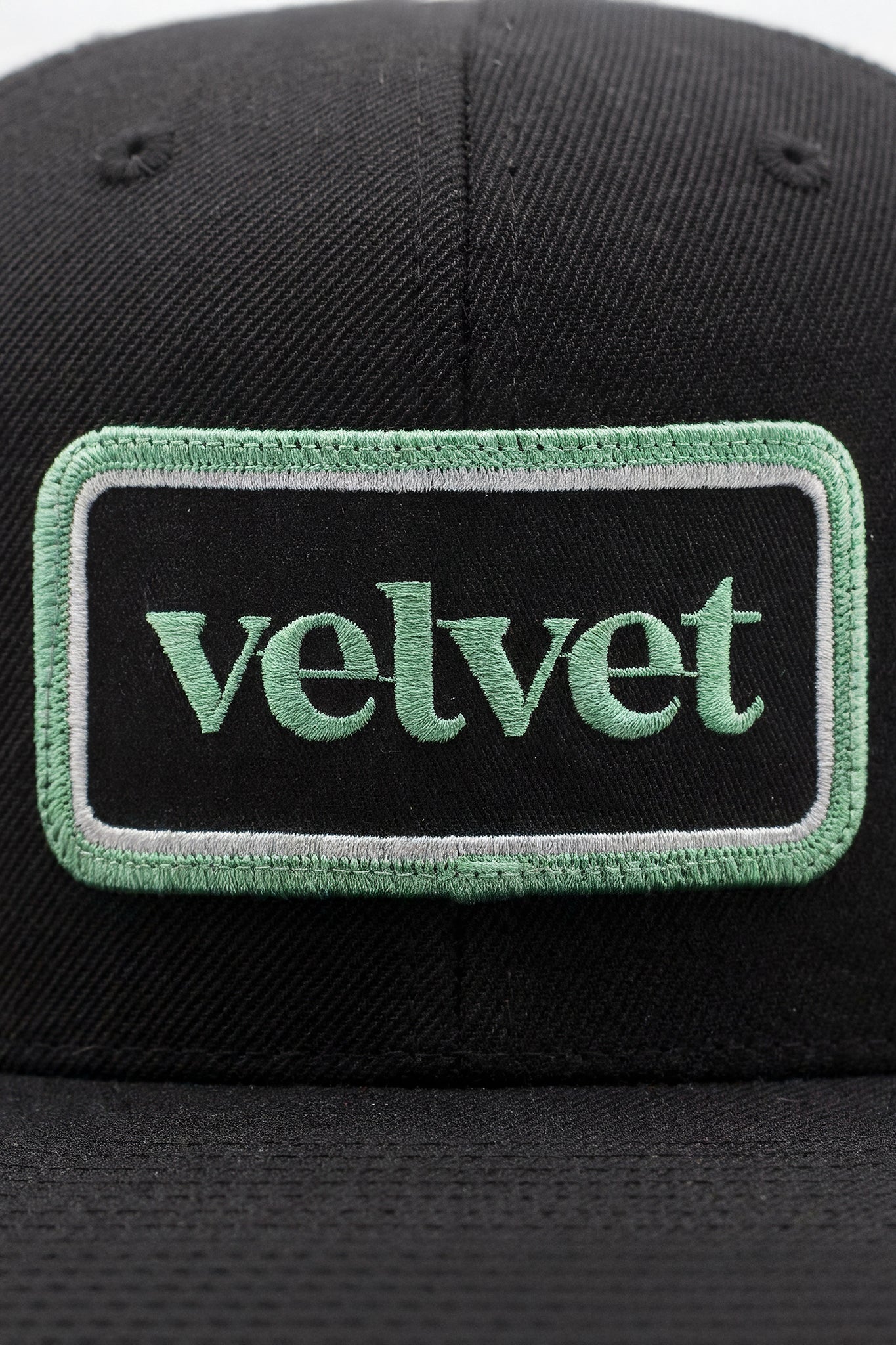 Black cap with a green 'velvet' patch on a white background