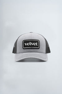 Gray and black cap with 'velvet' logo on a light gray background