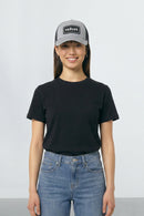 Person wearing a black t-shirt, blue jeans, and a gray cap with 'velvet' branding on a white background