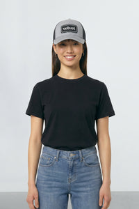 Person wearing a black t-shirt, blue jeans, and a gray cap with 'velvet' branding on a white background
