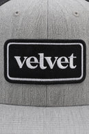 Gray cap with a black patch displaying the word 'velvet'.