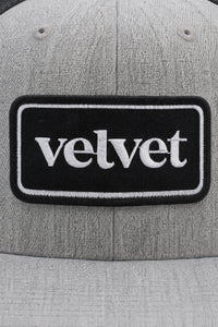 Gray cap with a black patch displaying the word 'velvet'.