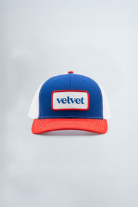 Blue and red cap with 'velvet' logo on a light gray background