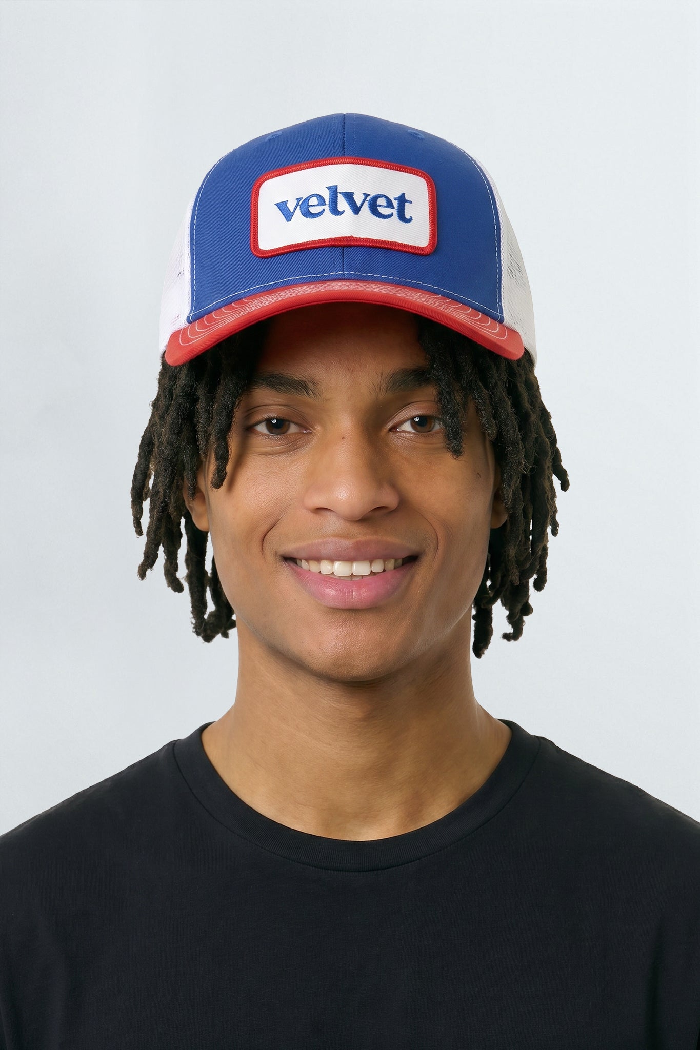 Person wearing a blue and red cap with 'velvet' logo on a white background