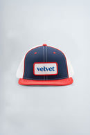 Navy and red cap with 'velvet' logo on a light gray background