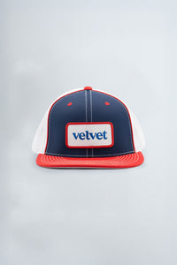 Navy and red cap with 'velvet' logo on a light gray background