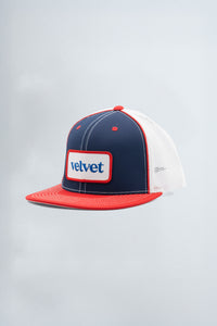 Trucker hat with red, white, and blue color scheme on a light gray background