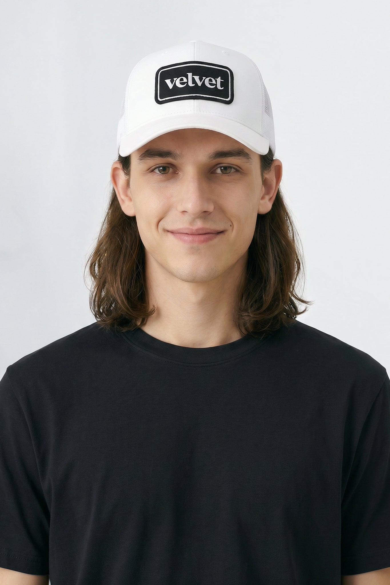 Person wearing a white cap with 'velvet' logo on a plain background