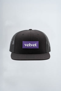 Black cap with a purple logo on a light  background