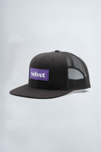 Black mesh cap with purple 'velvet' logo on a light background
