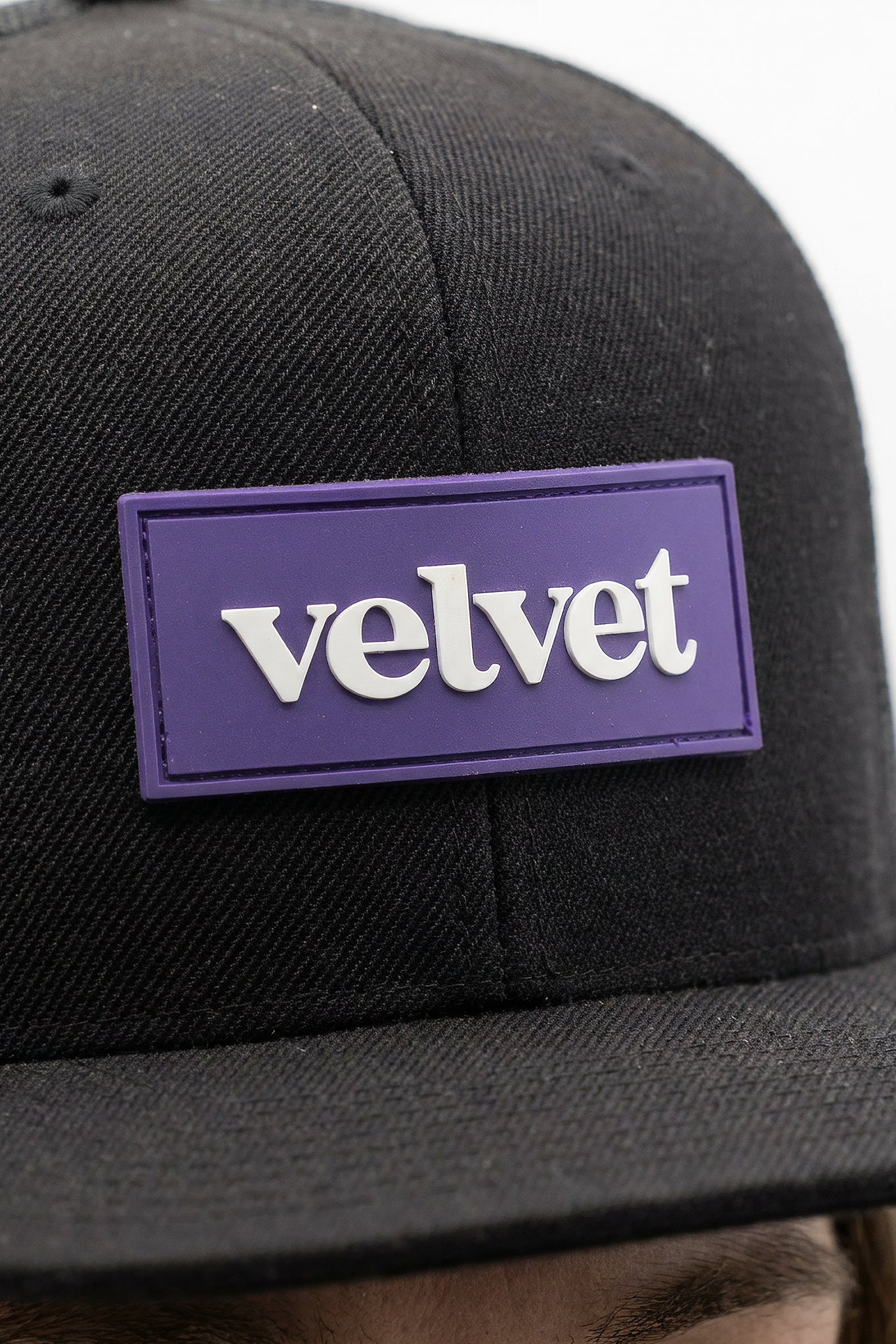 Black cap with a purple 'velvet' patch on a blurred background