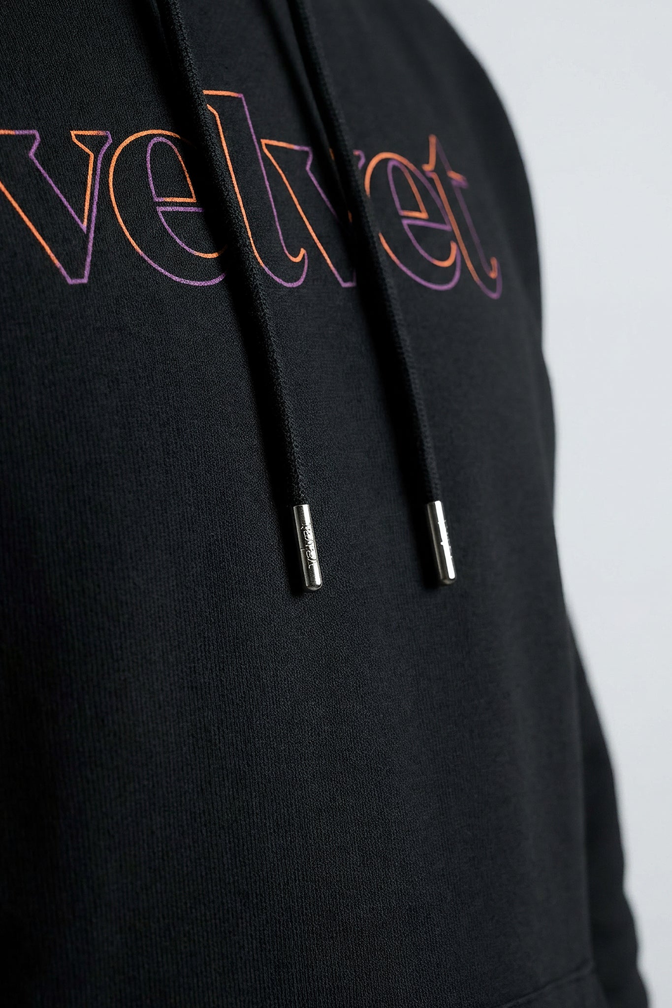 Black hoodie with colorful 'velvet' text on a light background