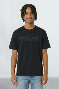Person wearing a black t-shirt with 'velvet' text on a plain background