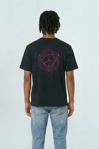 Person wearing a black t-shirt with a geometric design on the back, standing against a light background.