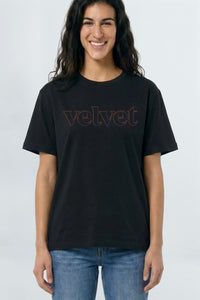 Person wearing a black t-shirt with 'velvet' text on a light
 background