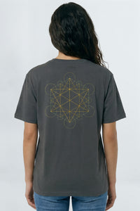 Person wearing a gray t-shirt with a geometric design on the back against a background