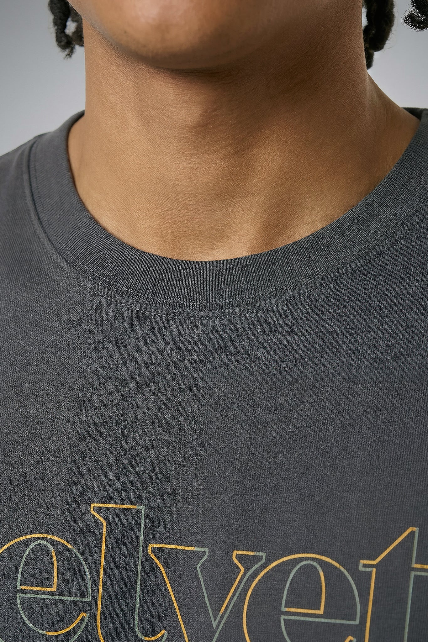 Close-up of a person wearing a gray t-shirt with 'velvet' printed on it.