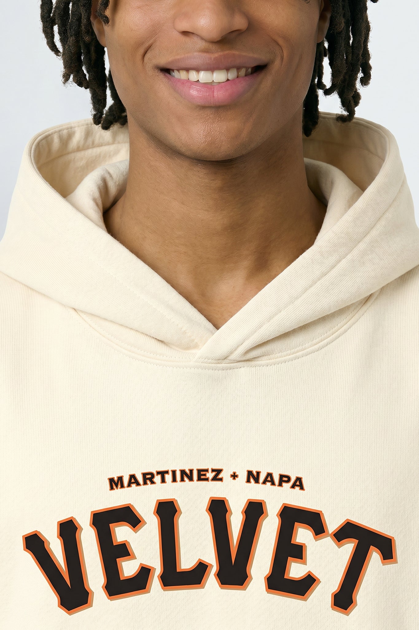 Person wearing a cream hoodie with 'Martinez + Napa Velvet' text on a light background