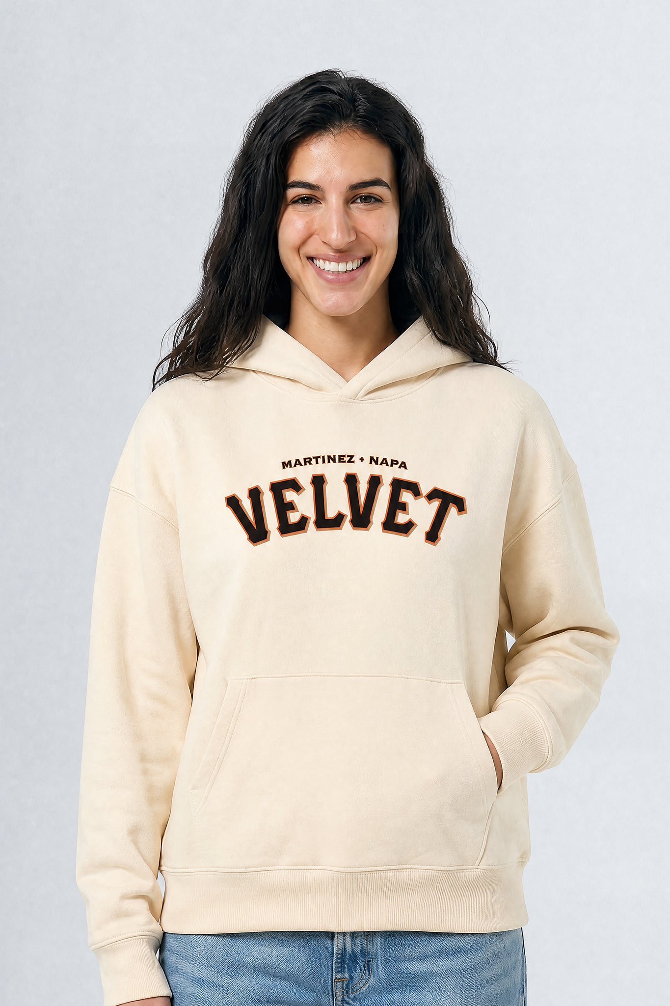 Woman wearing a cream hoodie with 'Martinez Napa Velvet' text on a plain background