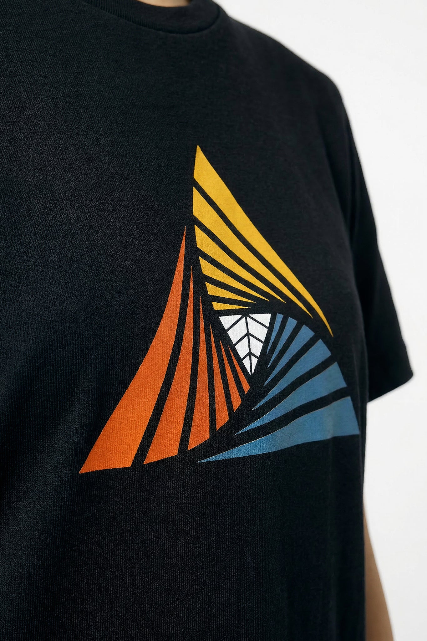 Black t-shirt with a colorful geometric design on a light background