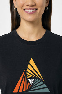 Person wearing a black t-shirt with a colorful geometric design on a plain background