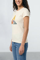 Person wearing a beige t-shirt with a colorful graphic design on a plain background