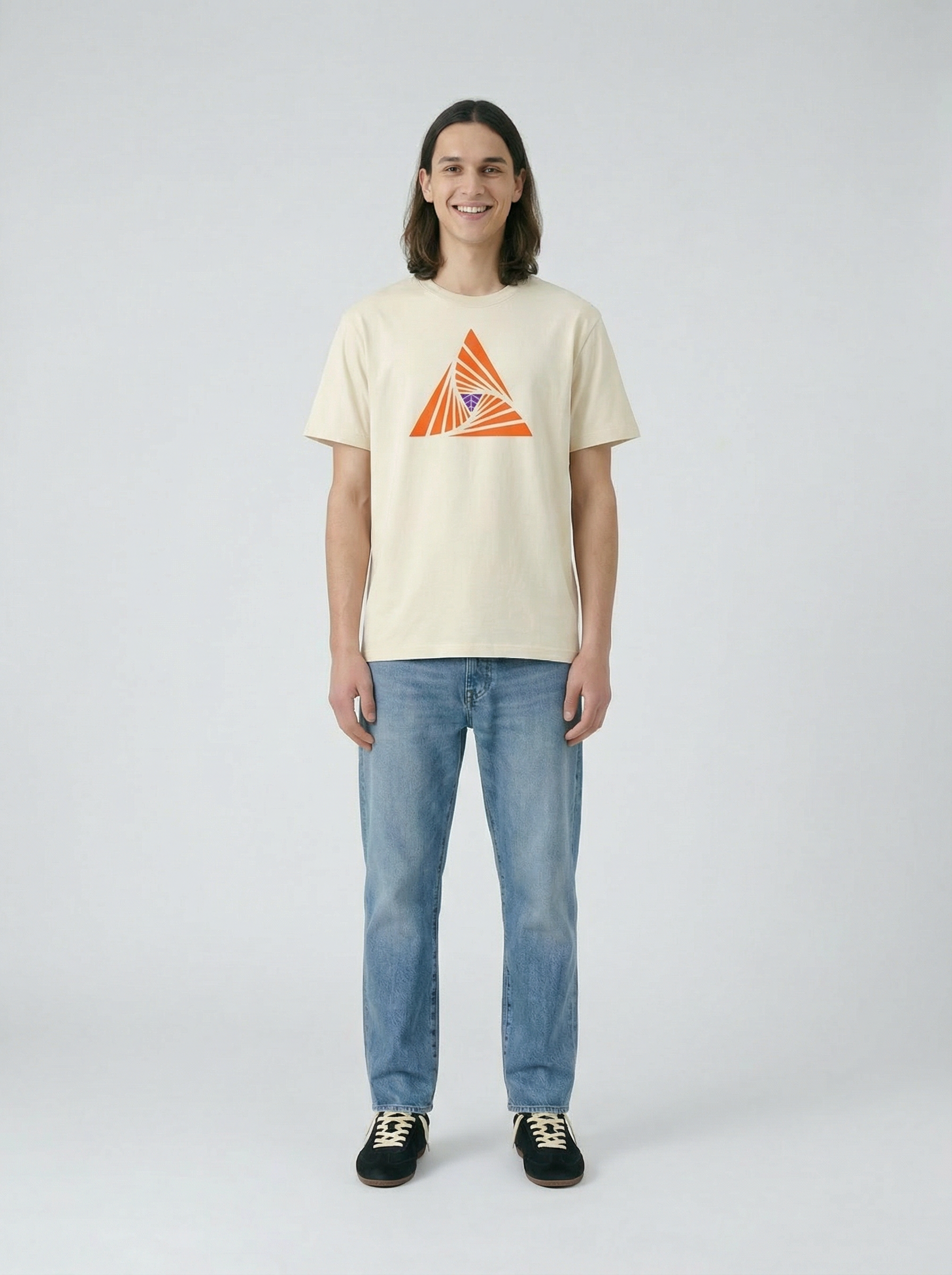 Person wearing a beige t-shirt with a geometric design and blue jeans on a light background