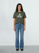 Person wearing a Khaki green t-shirt with a triangle design and blue jeans on a light background