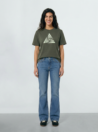 Person wearing a Khaki green t-shirt with a triangle design and blue jeans on a light background