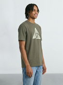 Man wearing a Khaki green t-shirt with a white geometric design on a plain background